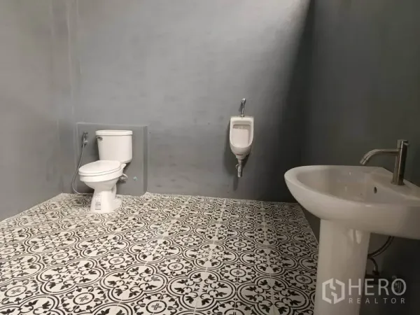 Warehouse for rent in Saphan Sung, Bangkok - Clean restroom inside the warehouse with patterned tile floor, toilet, urinal, and pedestal sink.