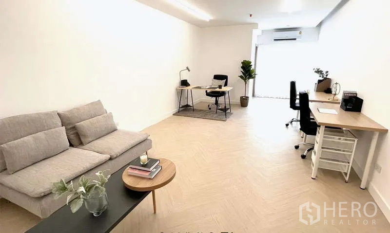 Office Space for rent in Watthana, Bangkok - Bright open office with sofa, work desks, and light wood herringbone flooring.