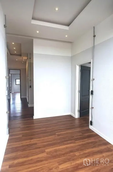 Home Office for rent or sale in Khlong Toei, Bangkok - Bright hallway with recessed lighting, white walls and wood flooring leading to multiple rooms.