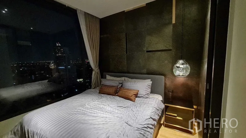 Condominium for rent in Watthana, Bangkok - Bedroom at night with a wide window overlooking Bangkok city lights.