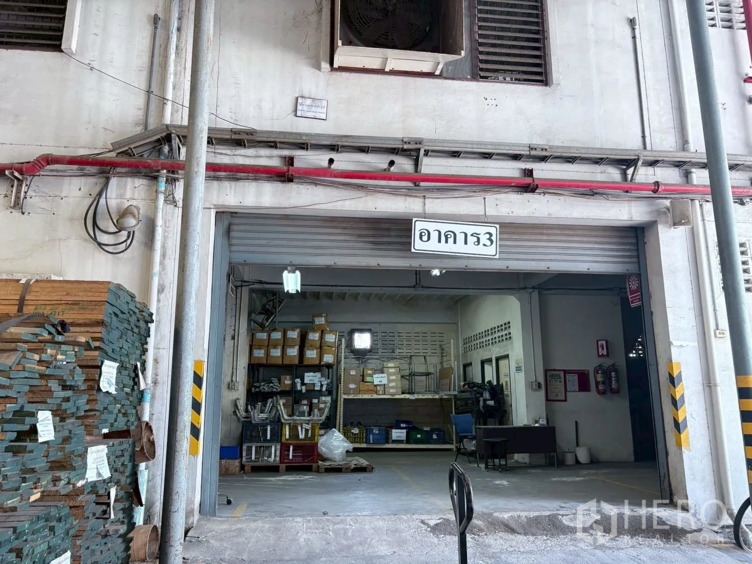 工厂 出租或出售在Bang Khun Thian, Bangkok - 仓库房入口，货架与物料，卷闸门半开。
