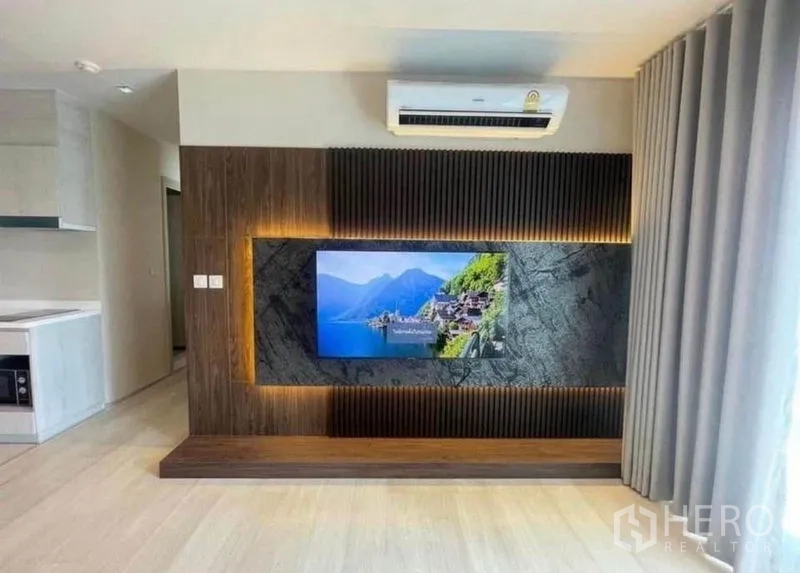Condominium for rent or sale - TV feature wall with LED lighting and air conditioner in the open-plan living area.