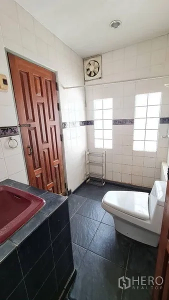 独立式住宅 出租在Lat Phrao, Bangkok - 卫生间铺砖，玻璃砖采光窗、排风扇与木门。