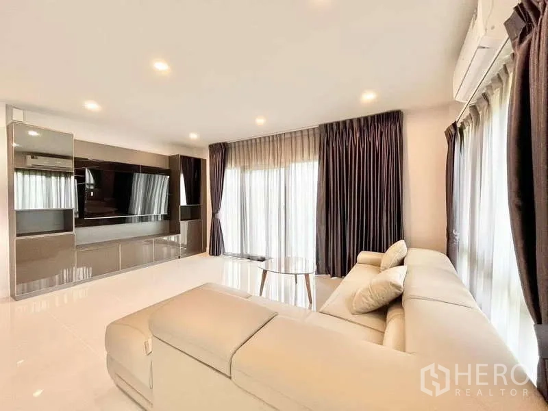 Detached House for rent in Don Mueang, Bangkok - Bright living room with media wall, large TV cabinet and corner sofa.