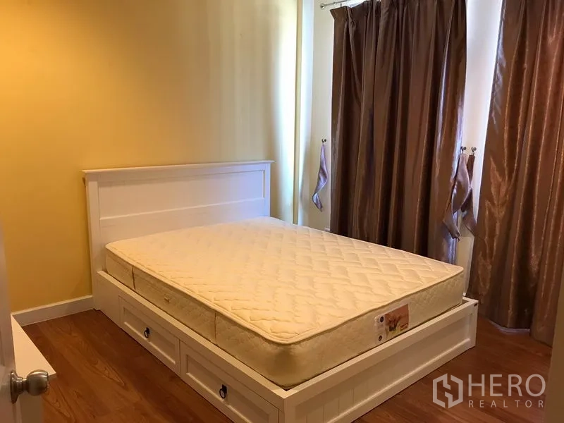 Townhouse for rent in Wang Thonglang, Bangkok - Second bedroom with white storage bed featuring drawers and brown curtains.
