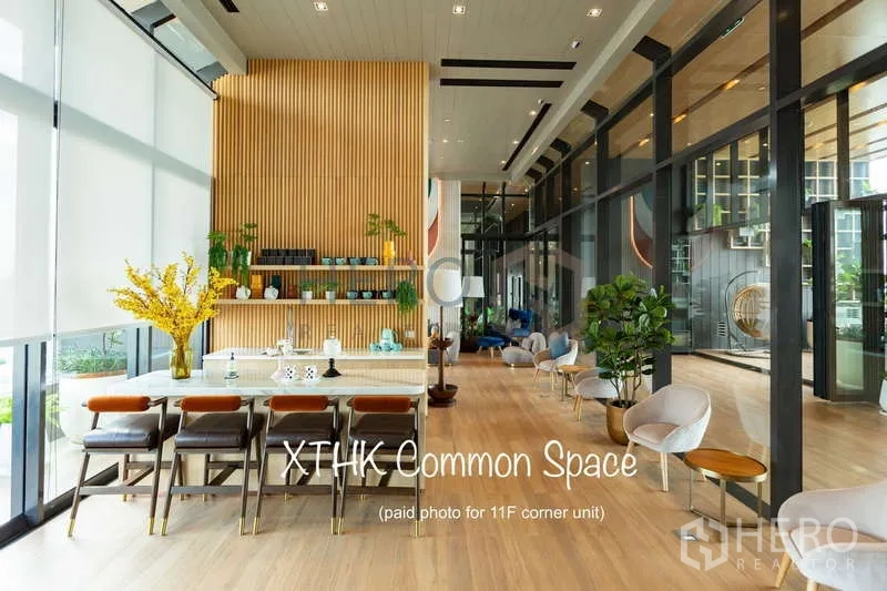Condominium for rent or sale - Double-height common lounge with long table, shelving and garden views at XT Huaikhwang.