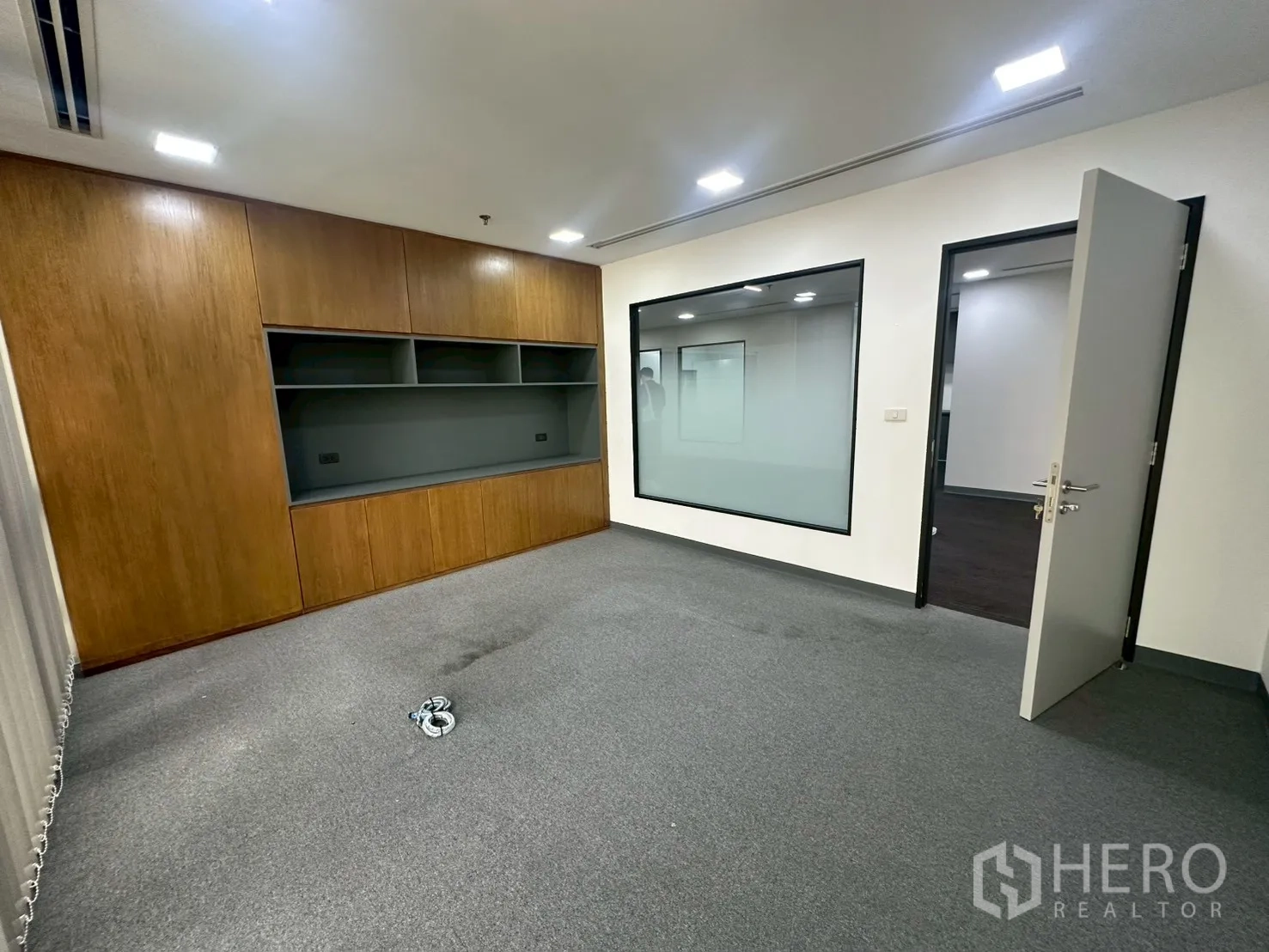 Office Space for rent - Executive office reverse view with large interior window and built-in wall unit.