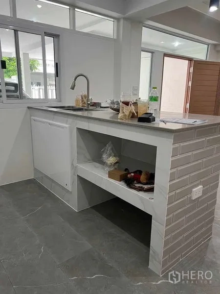 Townhouse for rent in Khlong Toei, Bangkok - Breakfast bar with sink and open shelving facing sliding windows.