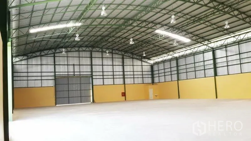 Warehouse for rent in Lat Krabang, Bangkok - Spacious warehouse interior with high steel-truss roof, LED lights, concrete floor, and large roller door.