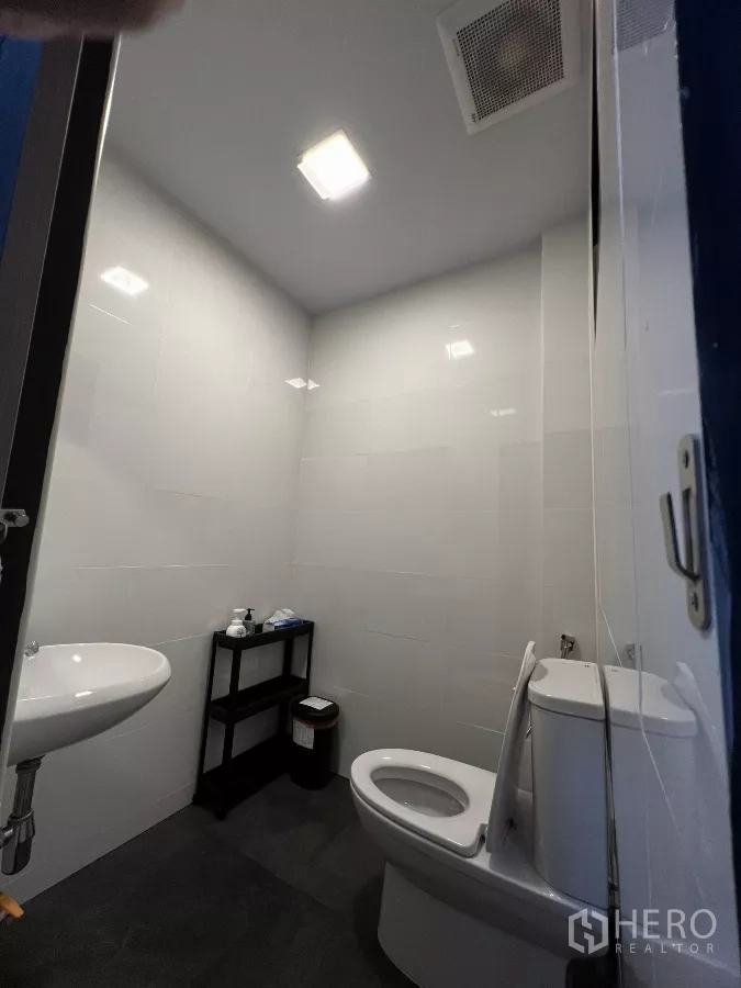 Home Office for rent in Pom Prap Sattru Phai, Bangkok - Modern restroom with toilet, wall tiles and compact sink.