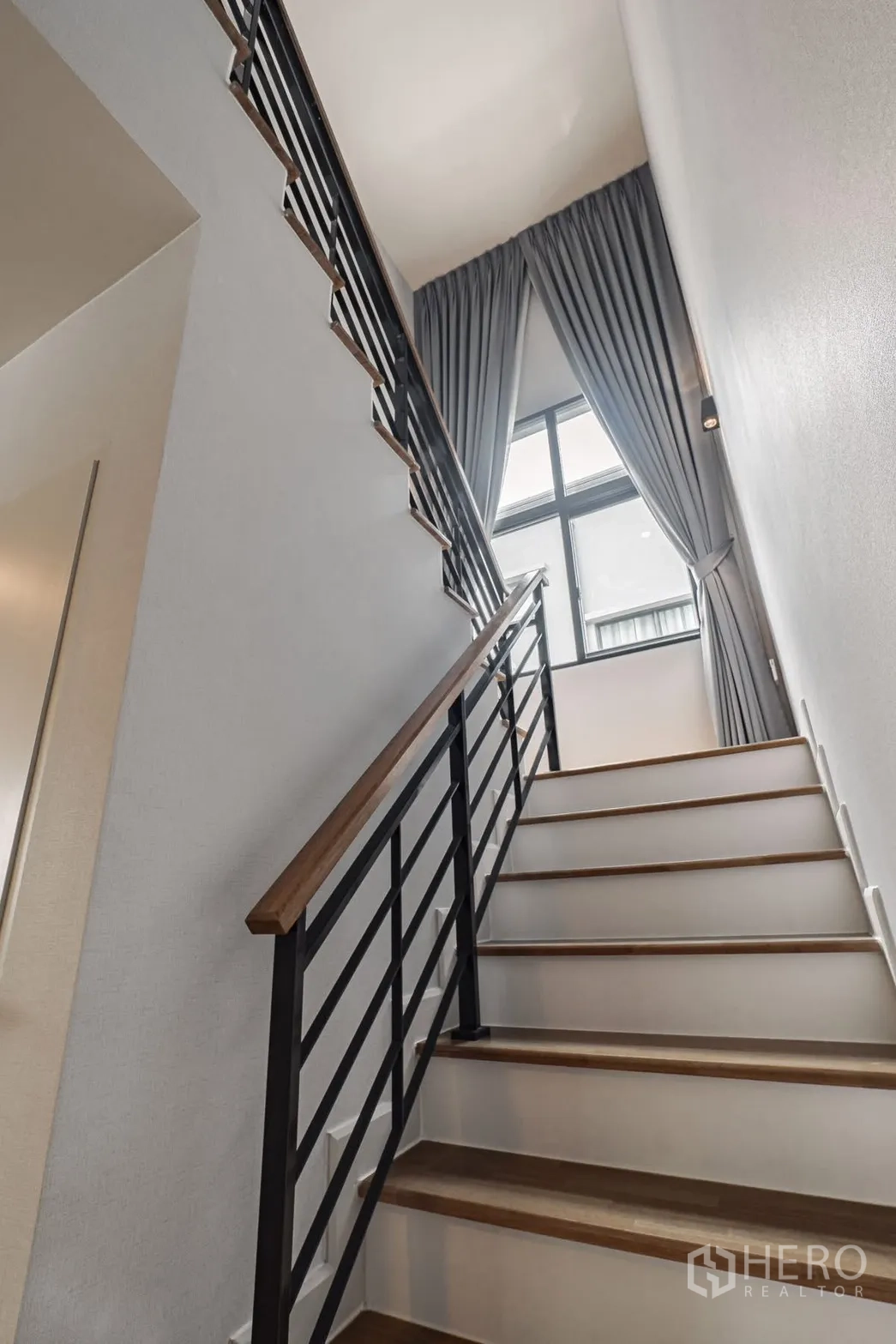 Detached House for rent in Bang Phli, Samut Prakan - Staircase with wooden steps and tall window draped with floor-length curtains.