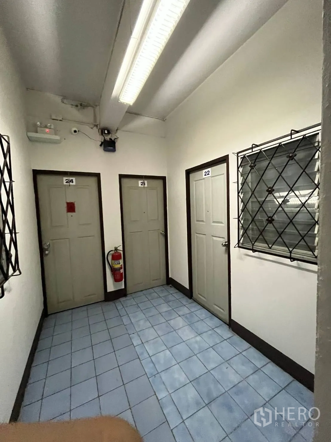 Shophouse for rent in Khlong Toei, Bangkok - Simple corridor with multiple doors, fluorescent lighting, and a safety extinguisher.