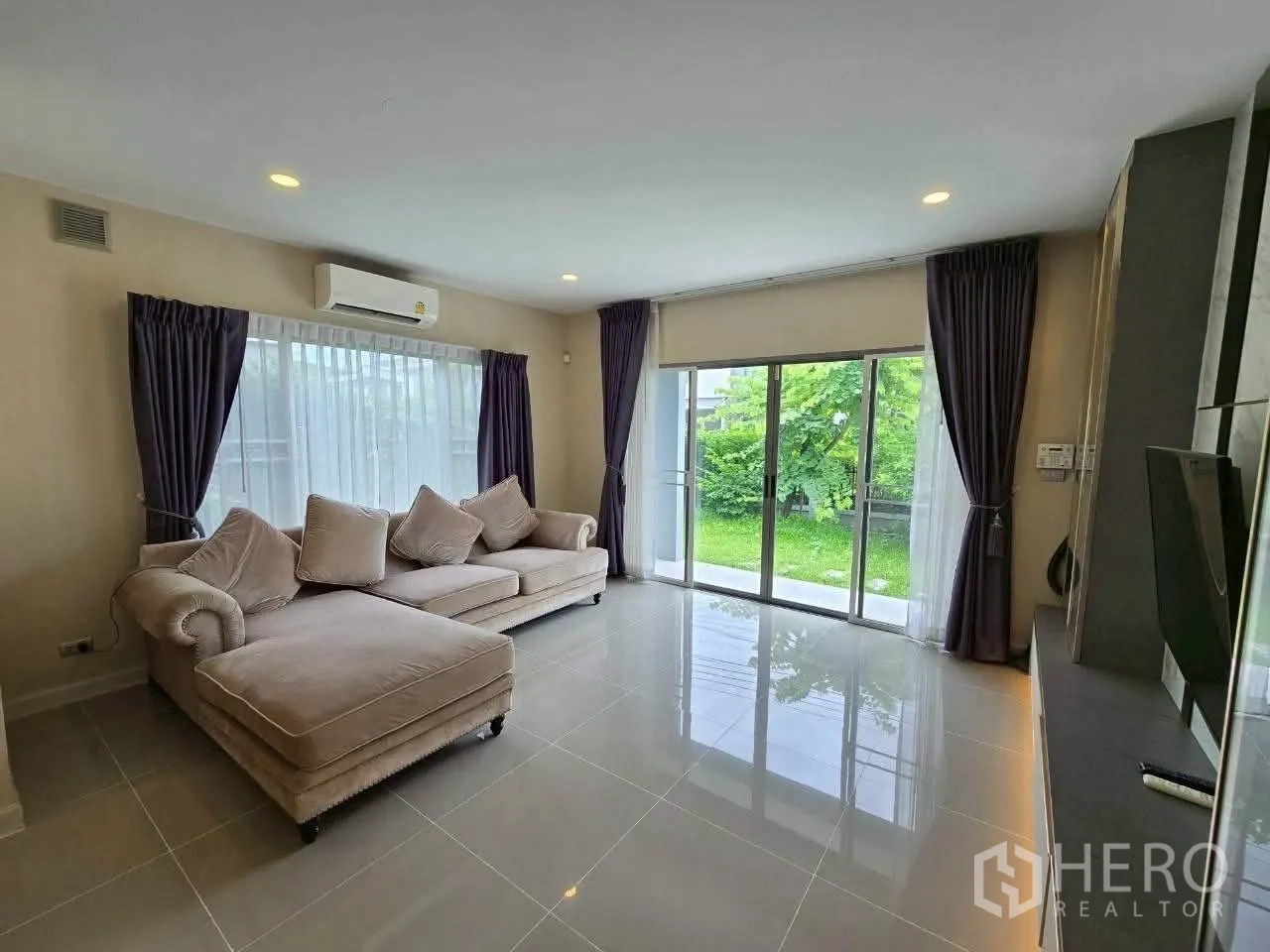Detached House for rent or sale in Lat Krabang, Bangkok - Bright living room with two sofas and sliding glass doors to lawn.