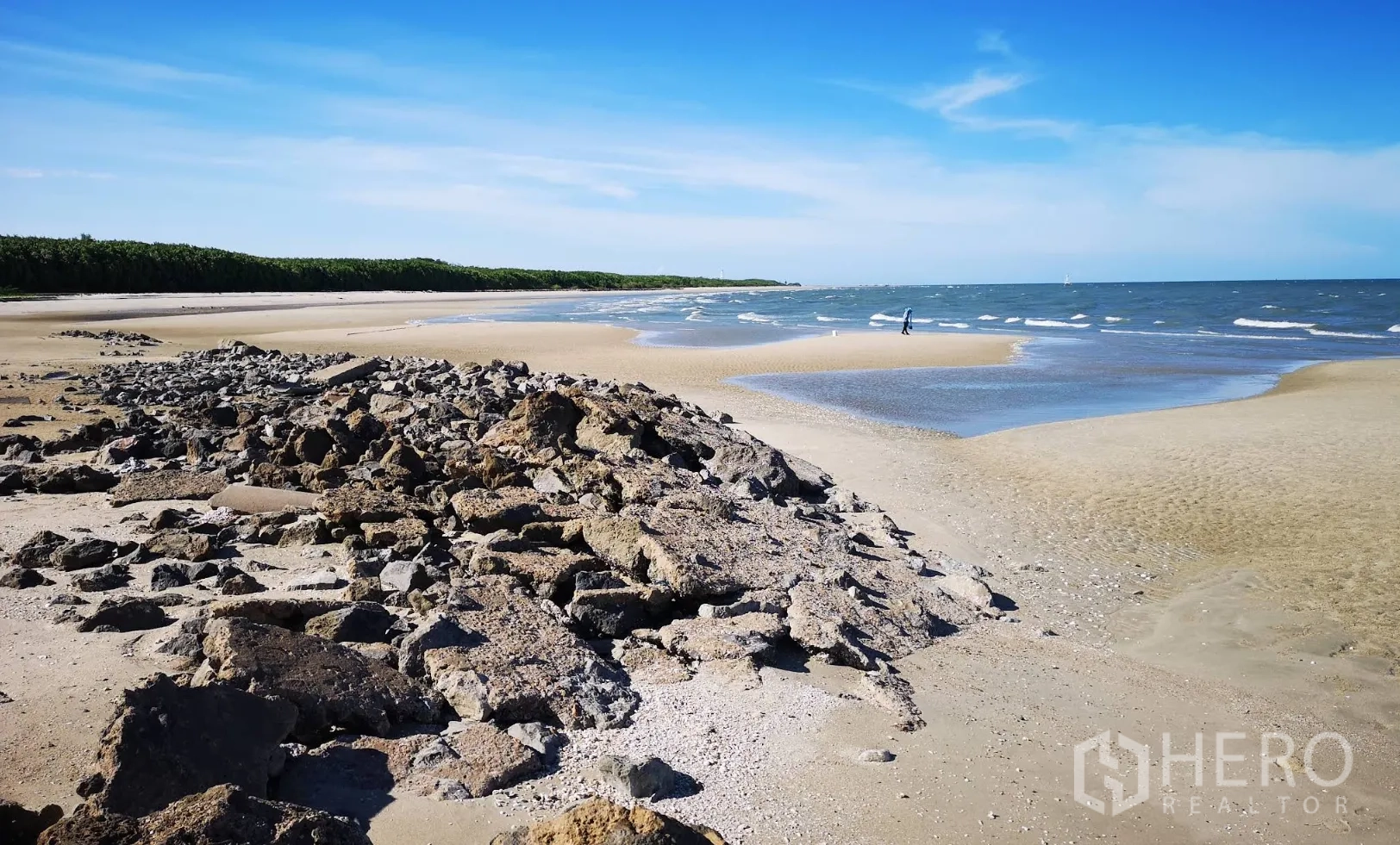 Land for rent or sale in Ban Laem, Phetchaburi - Sandy shoreline with rock embankment, tidal pools, and gentle waves.
