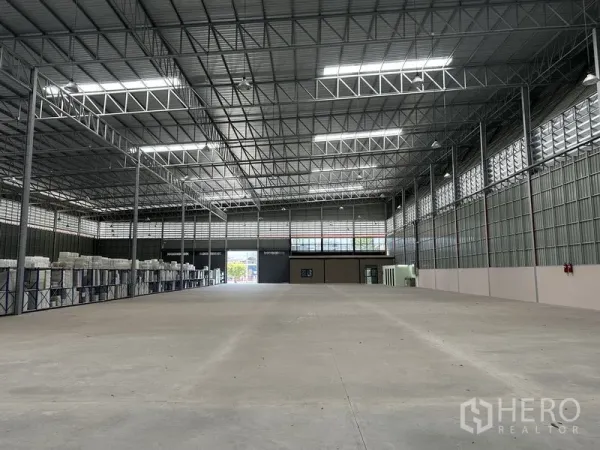 Factory for rent in Chachoengsao - Spacious clear‑span warehouse floor with high steel truss ceiling and skylights.