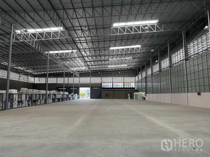 Factory for rent in Chachoengsao - Spacious clear‑span warehouse floor with high steel truss ceiling and skylights.