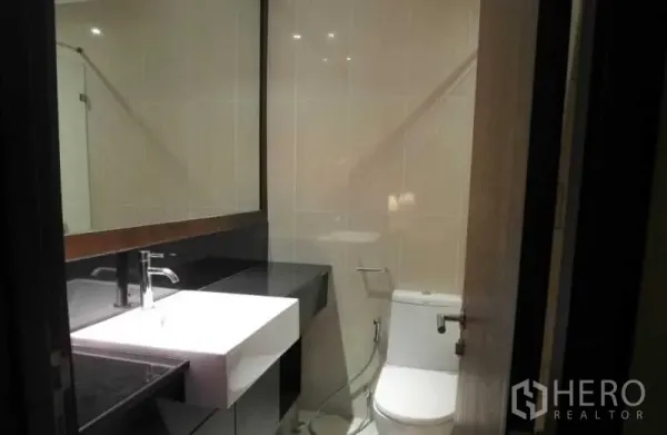 คอนโด ให้เช่าในSathon, Bangkok - ห้องน้ำสมัยใหม่ กระจกบานใหญ่ อ่างล้างหน้าเหลี่ยมบนท็อปหินสีดำ และโถสุขภัณฑ์