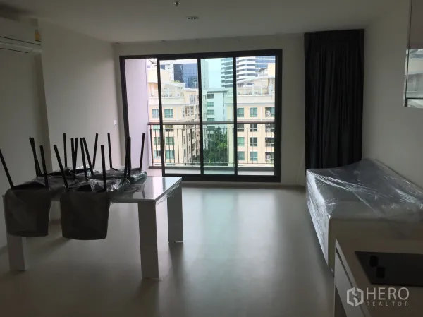 คอนโด ให้เช่าในKhlong Toei, Bangkok - ห้องนั่งเล่นสว่างพร้อมประตูกระจกสูงจรดเพดานเปิดสู่ระเบียงชมวิวเมือง