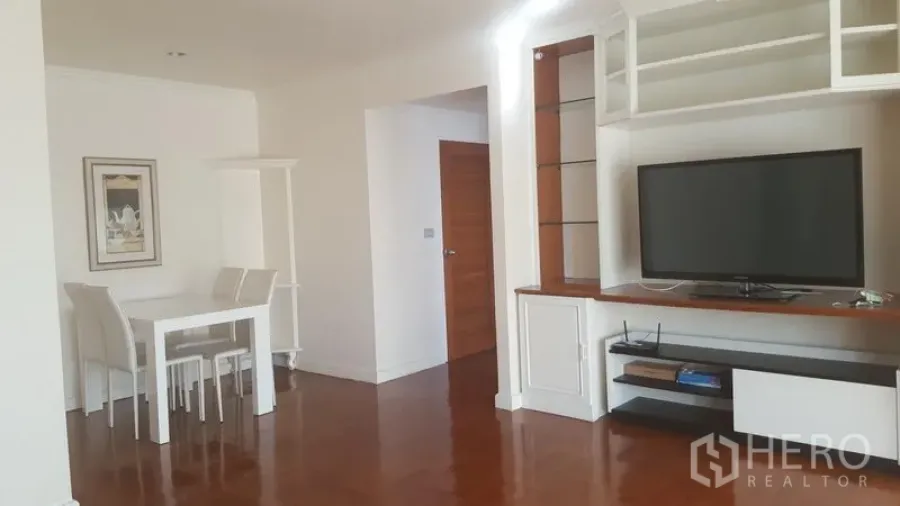 Condominium for rent in Watthana, Bangkok - Open-plan living and dining area featuring a built-in TV cabinet, shelving and polished wood flooring.