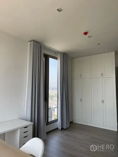 Condominium for rent in Bang Kho Laem, Bangkok - Room with tall white wardrobe and window with curtains.