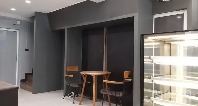 อาคารพาณิชย์ ให้เช่าในChatuchak, Bangkok - มุมที่นั่งโต๊ะกลมไม้ติดผนังโทนเข้ม ใกล้บันไดและตู้แช่ตั้งพื้น
