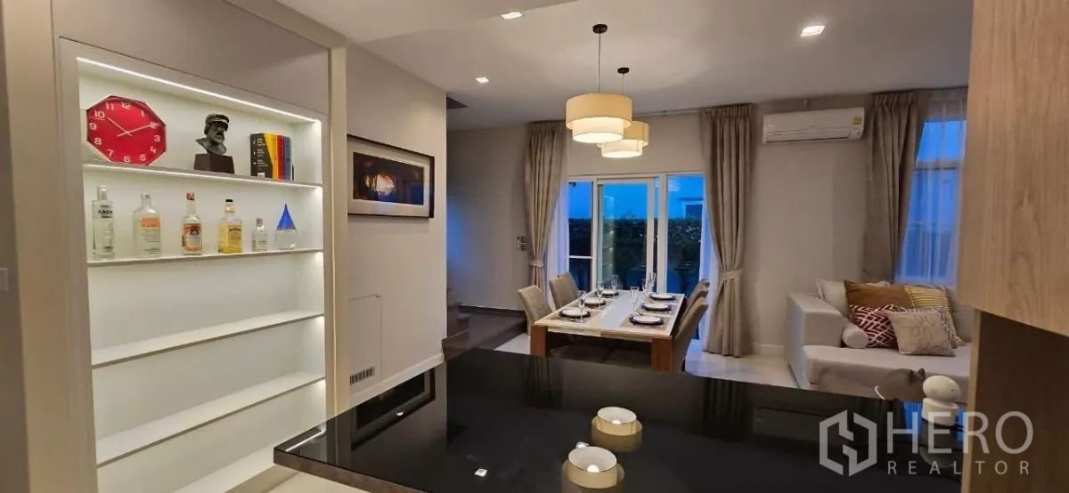 Detached House for rent in Samut Prakan - Six-seat dining area beside illuminated display shelves and sliding doors to the garden.