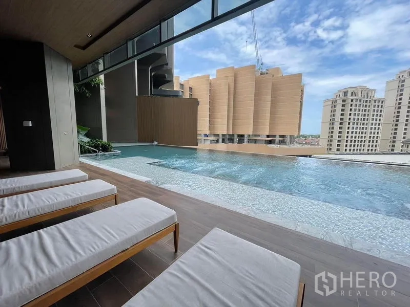 Condominium for rent in Samut Prakan - Poolside sunbeds under shade beside a shallow leisure pool.