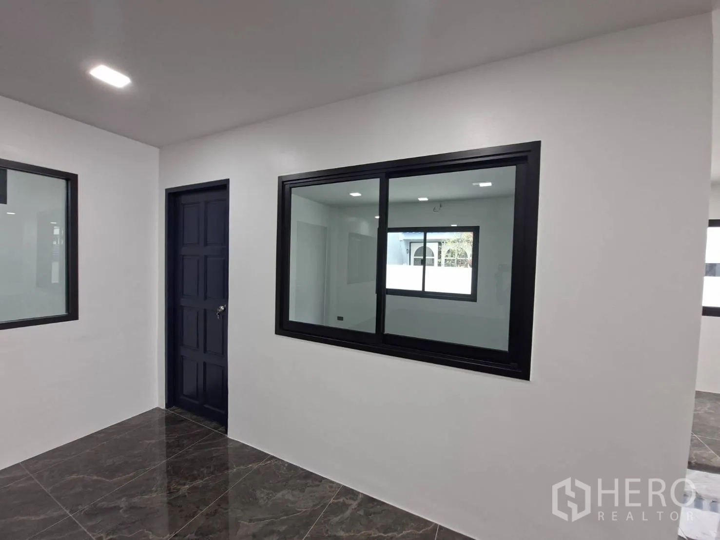 家庭办公室 for rent in Phra Khanong, Bangkok - 室内走廊，白墙与黑框窗户和房门。