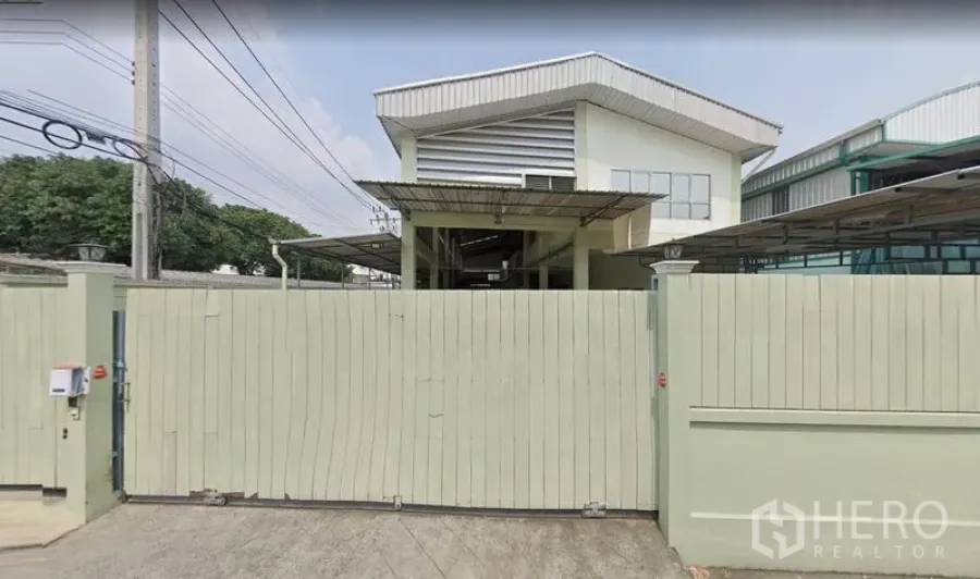 货栈 出租在Khan Na Yao, Bangkok - 曼谷Khan Na Yao区带高尖屋顶与安全围墙的仓库正门外观。