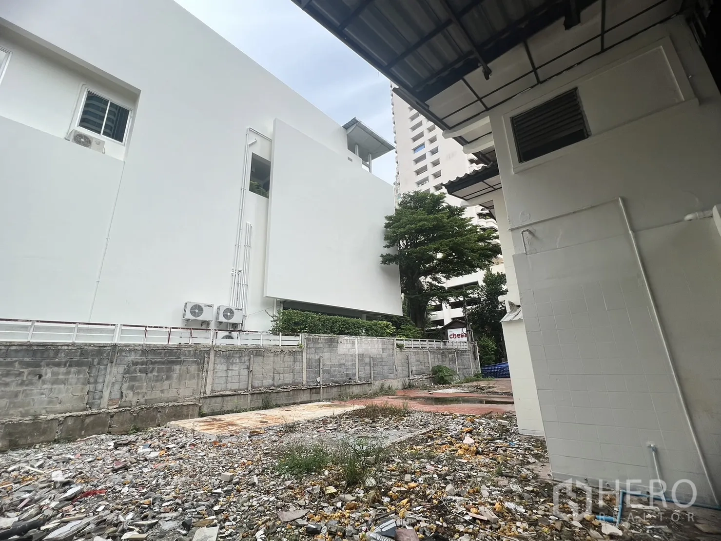 零售空间 出租在Watthana, Bangkok - 室外空地有碎石与杂物，位于相邻建筑之间的围墙内。