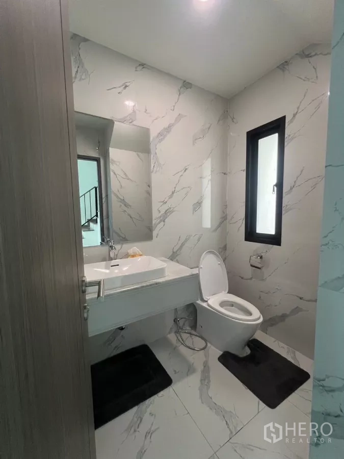 บ้าน ให้เช่าในLat Phrao, Bangkok - ห้องน้ำแขกสไตล์โมเดิร์น ผนังลายหินอ่อน หน้าต่างเล็ก อ่างล้างหน้าและโถสุขภัณฑ์สีขาว