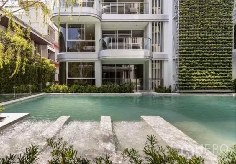 Condominium for rent in Watthana, Bangkok - Facade overlooking pool with vertical green wall and cascading water.
