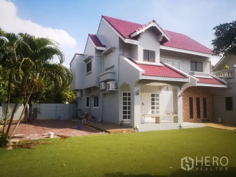 独立式住宅 出租在Samut Prakan - 两层独栋外观，红色瓦顶与开阔草坪。
