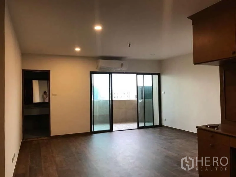 คอนโด ขายในWatthana, Bangkok - พื้นที่นั่งเล่นขนาดใหญ่ พื้นไม้เข้ม และประตูกระจกบานเลื่อนไปยังระเบียง