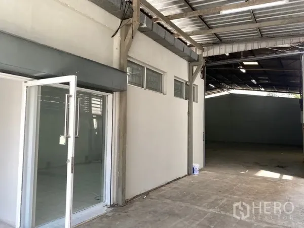 Warehouse for rent in Chatuchak, Bangkok - Glass entry to the office area beside an open‑plan warehouse under a metal roof.