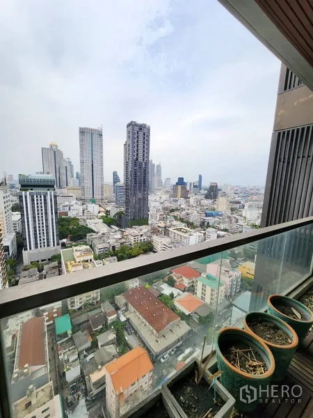公寓 出租在Bang Rak, Bangkok - 高楼层阳台玻璃护栏，俯瞰曼谷城市天际线与街区。