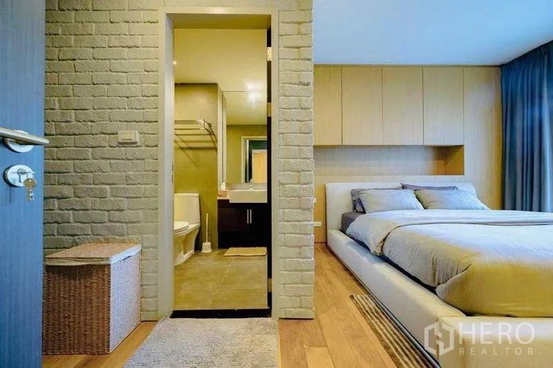 Condominium for rent in Watthana, Bangkok - Bedroom suite with brick wall leading to bathroom with vanity and shower.