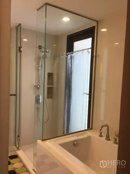 Condominium for rent in Watthana, Bangkok - Bathroom featuring a glass-enclosed shower next to a soaking bathtub and window.