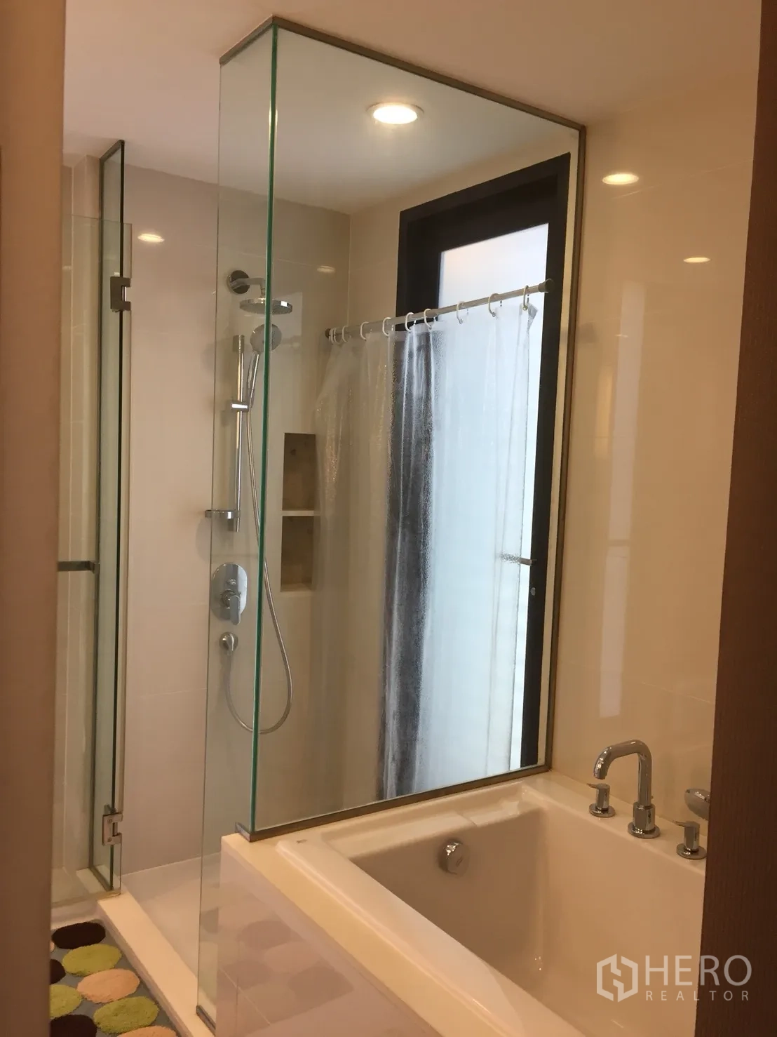 Condominium for rent in Watthana, Bangkok - Bathroom featuring a glass-enclosed shower next to a soaking bathtub and window.