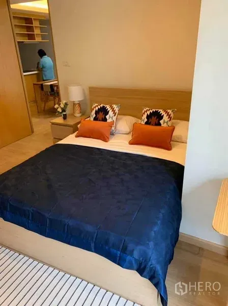 คอนโด ให้เช่าในWatthana, Bangkok - ห้องนอนหลักโทนอุ่น เตียงผ้าปูสีน้ำเงิน เฟอร์นิเจอร์ไม้และแสงไฟนุ่มนวล