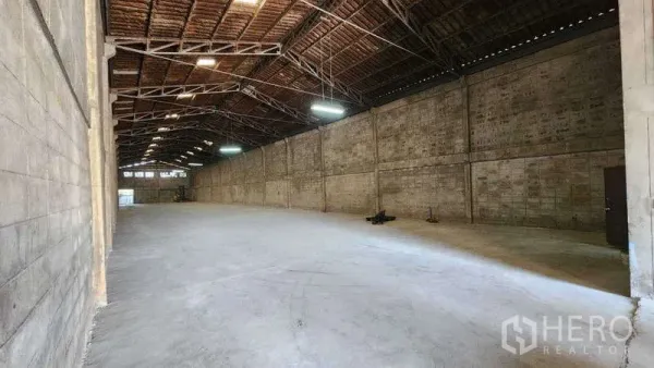 Warehouse for rent in Nong Khaem, Bangkok - Long open storage bay with bright lighting and ventilated brick walls.