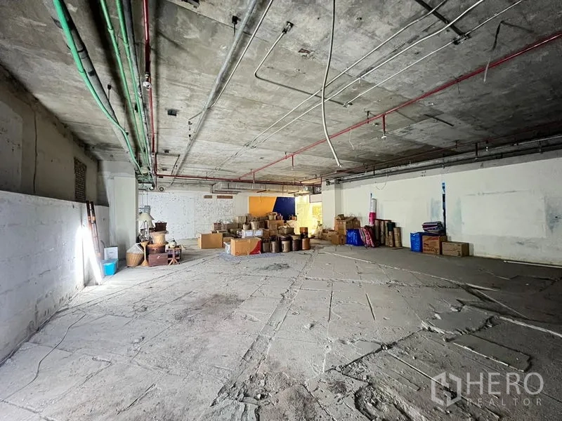 零售空间 出租 - 宽阔未装修商业空间，裸露天花管线与散放的纸箱。