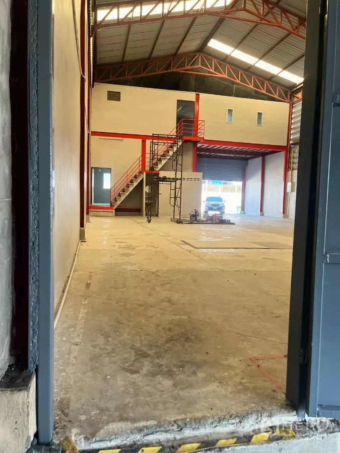 Warehouse for rent in Lat Lum Kaeo, Pathum Thani - Main warehouse hall with steel truss roof, mezzanine level, stairs, and large roller shutter.