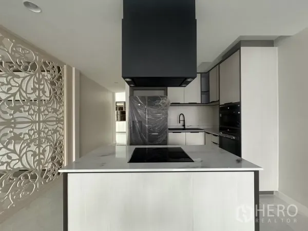 联排别墅 出租在Watthana, Bangkok - 当代厨房，岛台大理石面、感应灶与黑色油烟机。