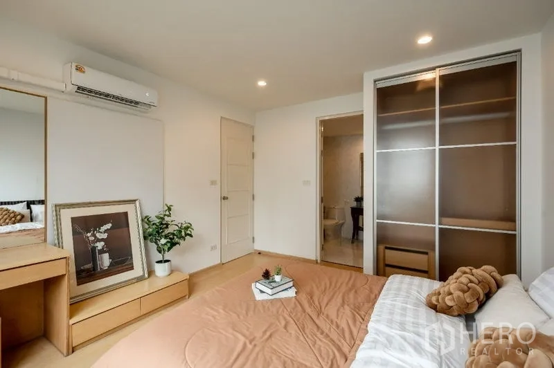 Condominium for sale in Watthana, Bangkok - Master bedroom showing built-in wardrobe, vanity and entrance to an ensuite bathroom.
