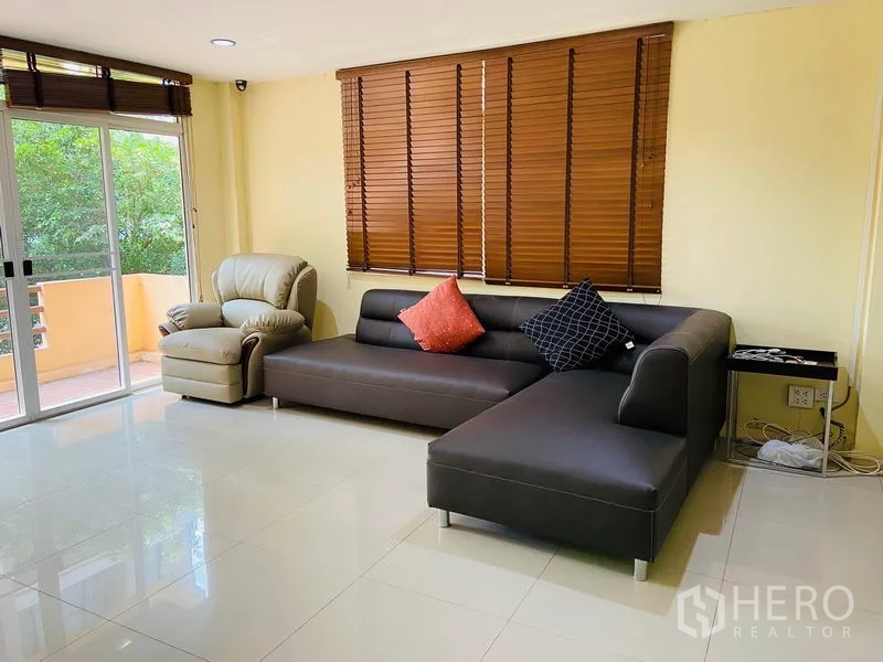 บ้าน ให้เช่าในWatthana, Bangkok - ห้องนั่งเล่นโซฟารูปตัวแอล เก้าอี้เอนกาย มู่ลี่ไม้ และประตูบานเลื่อนออกระเบียง