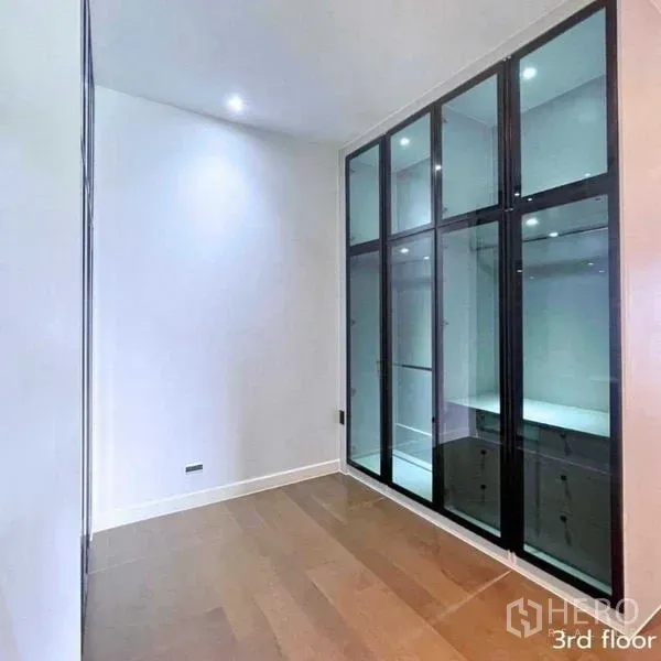 Detached House for rent in Bang Kapi, Bangkok - Compact walk-in closet with glass-front wardrobes and recessed lighting.