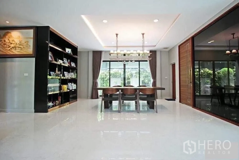 Detached House for rent in Bang Khae, Bangkok - Open dining space with long table, chandelier and sliding glass doors to the garden.