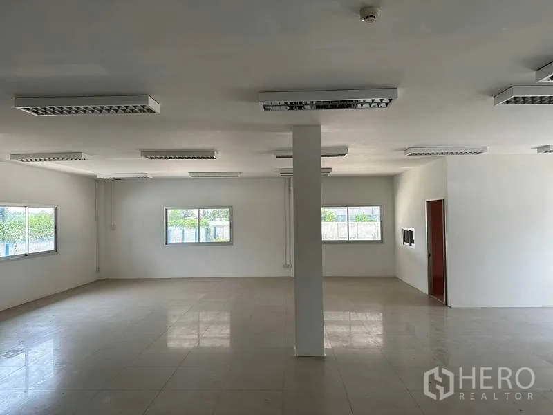 Warehouse for rent in Samut Prakan - Bright office room with tiled floors, white walls and multiple windows.