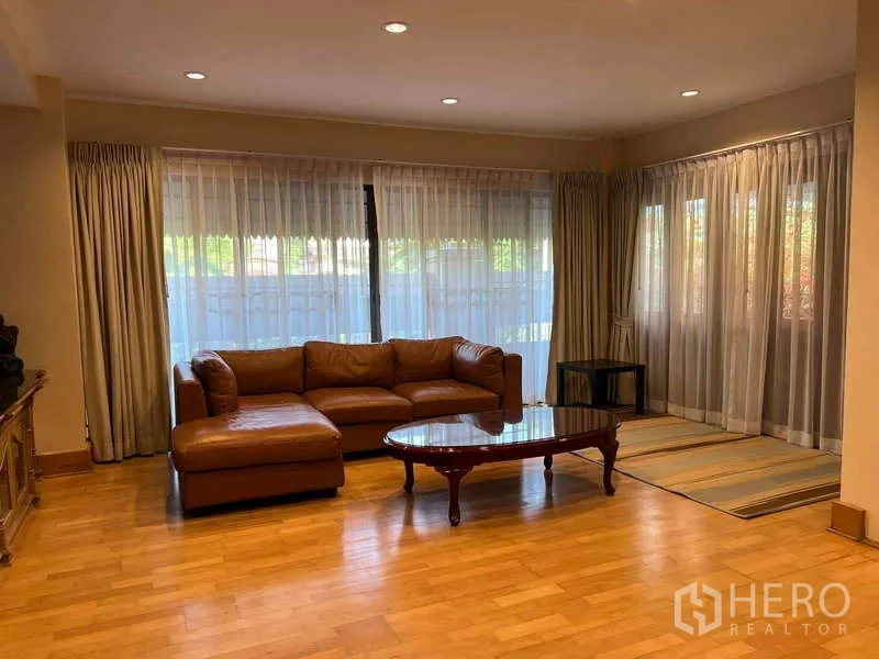 ทาวน์เฮาส์ ให้เช่าในKhlong Toei, Bangkok - ห้องนั่งเล่นที่สอง โซฟาหนังเข้ามุม พื้นไม้ และม่านโปร่ง